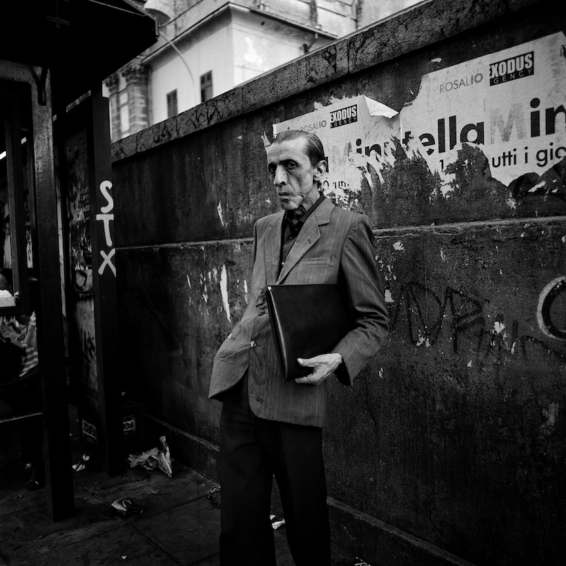 A man is waiting for the bus at a vandalised bus top inb Palermo. March 2009