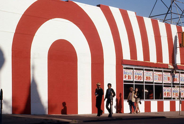 red_and_white_striped_storefront_with_passersby_attrib_to_arthur_stross_around_1970